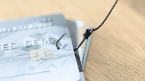 How to spot a pension scam? Image depitcts a pile of debit cards, with a fishing hook piercing the top card.