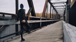 How to prepare for the 2027 pension changes? Image shows a jogger at one end of a bridge with his back to camera, looking ahead. He is stretching one of his legs in preparation the what's ahead.