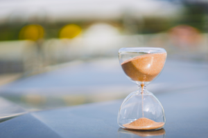 Should you delay your State Pension? What are the benefits? Image shows a sandtimer with orange sand running down.